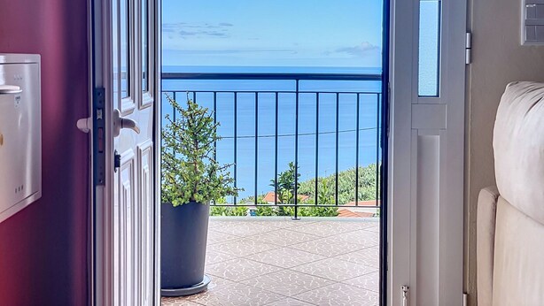 A room with a view of the sea through a balcony door. - Ocean Serenity House by Atlantic Holiday (Ribeira Brava)