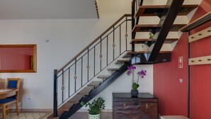A staircase with a black railing, a wooden bench, a small table, and a potted plant. - Ocean Serenity House by Atlantic Holiday (Ribeira Brava)