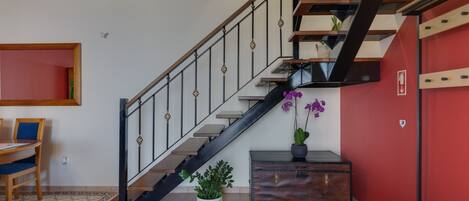 Eine Treppe mit schwarzer Geländer, eine Holzbank, ein kleiner Tisch und ein Blumentopf.