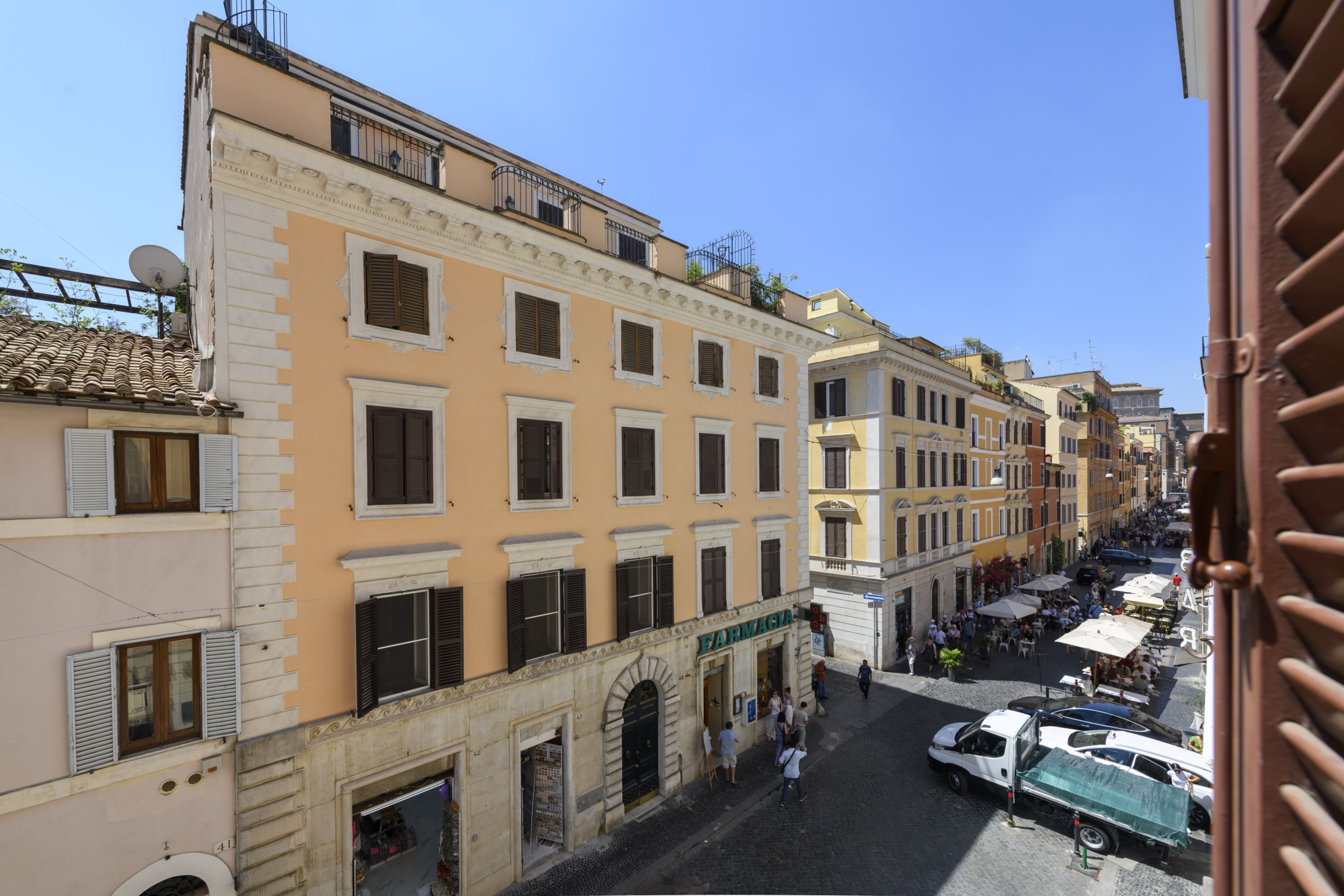 A street view with buildings, a pharmacy, and parked cars.