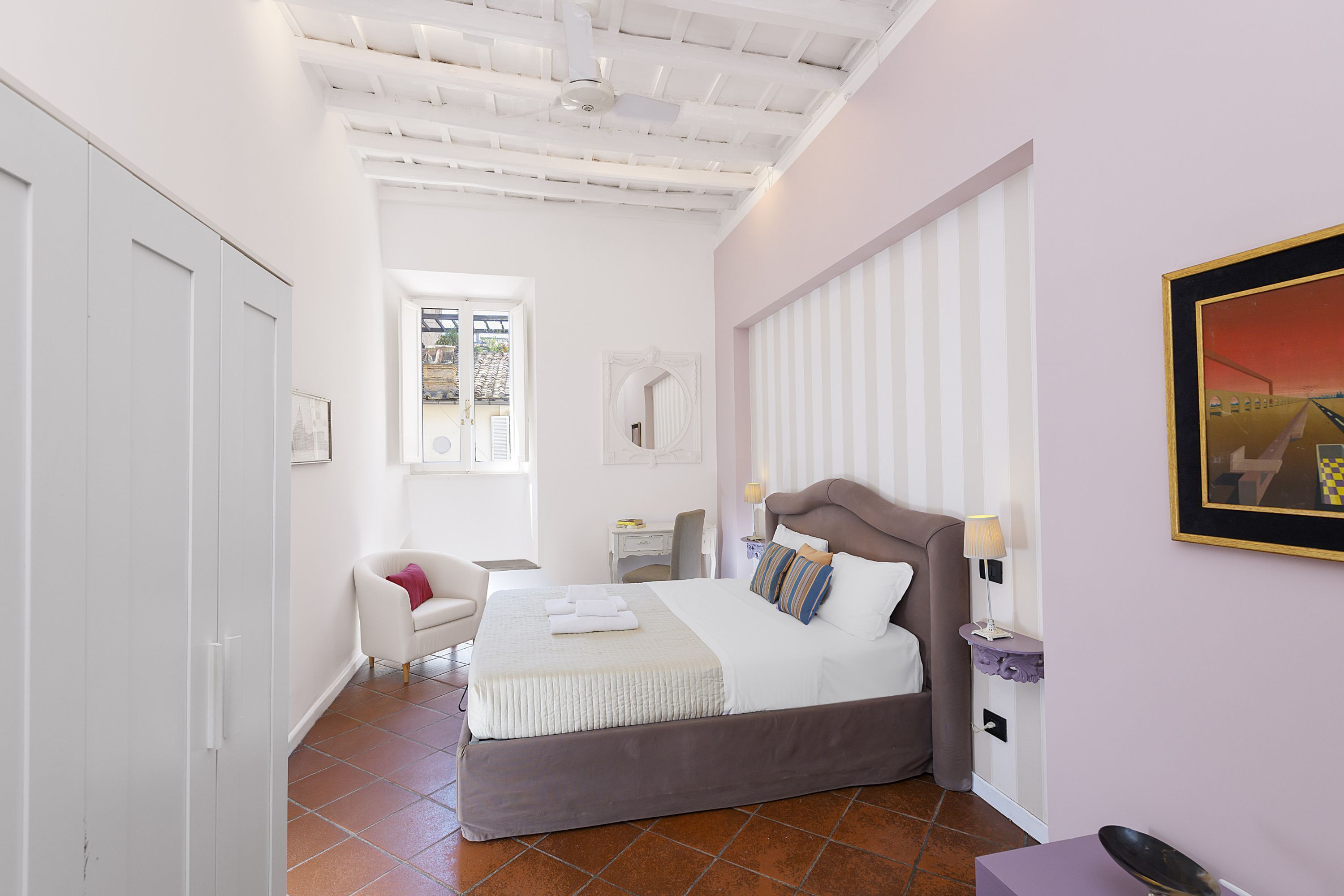 A bedroom with a bed, bedside table, chair, and a window.