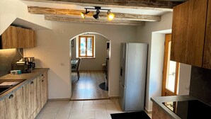Eine Küche mit Holzschränken, einem Kühlschrank und einem Essbereich mit Tisch und Stühlen.