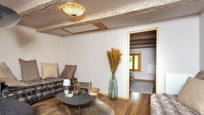Ein gemütliches Wohnzimmer mit einer Couch, einem Couchtisch und einer Vase mit Trockenpflanzen.