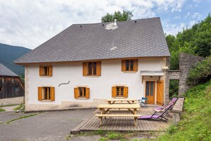 A two-story house with a sloped roof, wooden shutters, and a stone wall. - L'écrin de Brévardière (Saint-Pierre-de-Chartreuse)