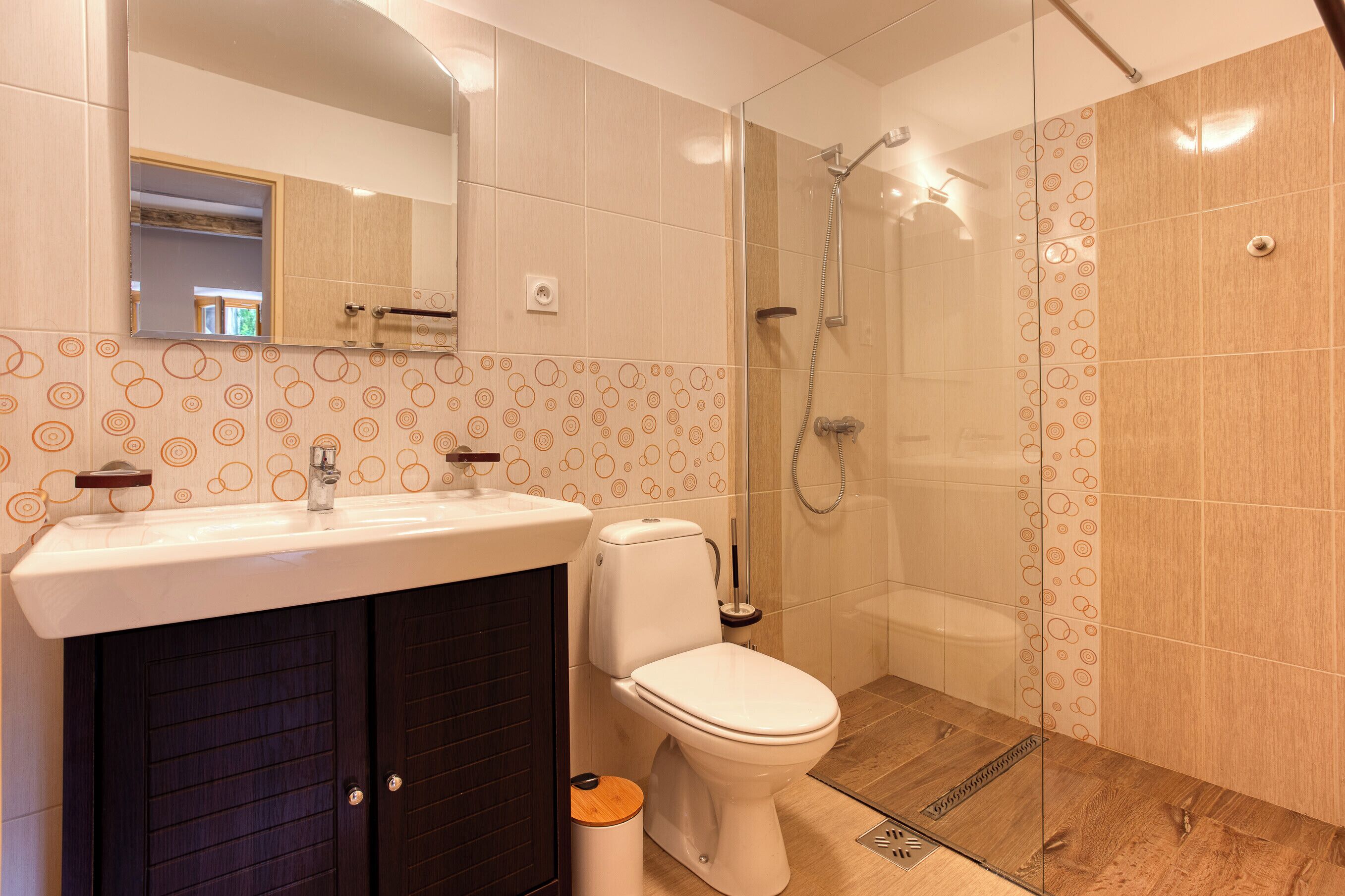 Een moderne badkamer met een douchecabine van glas, een toilet en een wastafel met spiegel erboven.