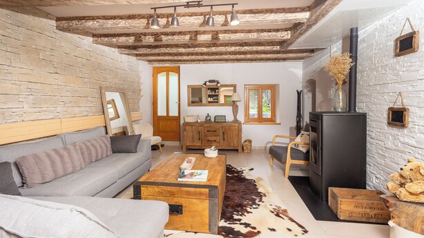 Ein gemütliches Wohnzimmer mit Steinwand, Holzboden, einer Couch, einem Couchtisch und einem Kamin.