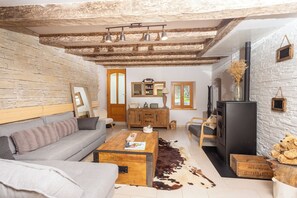 Uma sala de estar acolhedora com parede de pedra, teto de madeira, sofá, mesa de centro e lareira.