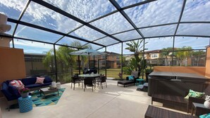 Un patio techado al aire libre con techo de vidrio, una mesa redonda, sillas, un sofá y un jacuzzi.