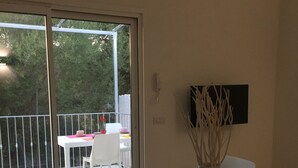 Un comedor con una mesa, sillas, un florero con ramas y un control remoto.