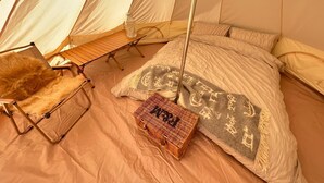 Ein Zelt mit Bett, Stuhl und Korb.