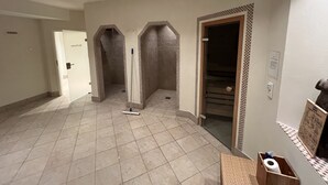 Un corridoio d'hotel con pavimento piastrellato, uno straccio e una scatola di legno con un rotolo di carta igienica.