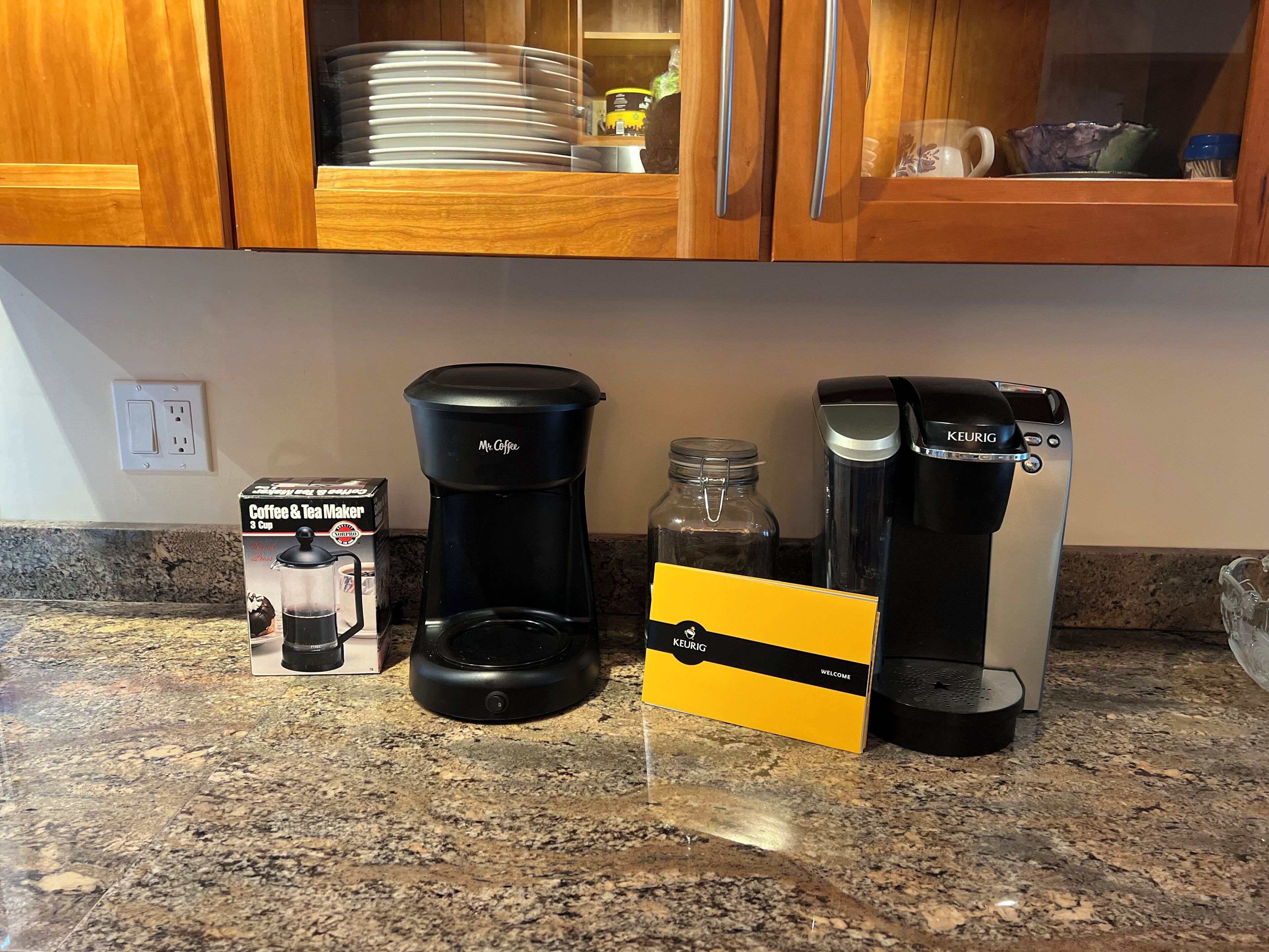 A kitchen counter with a coffee maker, a Keurig coffee maker, and a coffee maker box.