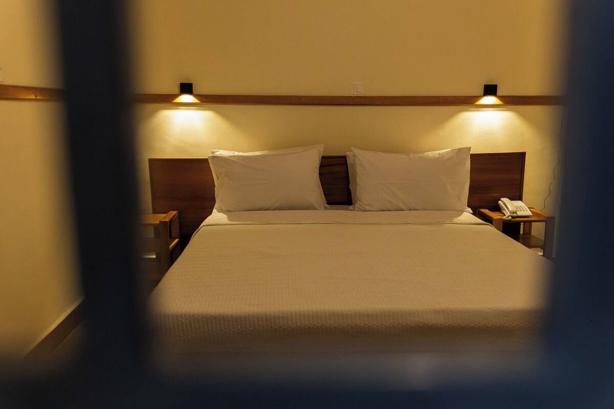 Ein Hotelzimmer mit einem Bett, zwei Nachttischen, einem Telefon und Wandleuchten.