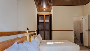 A hotel room with a wooden headboard, a bed with white bedding, a small bedside table, and a wardrobe. - Amakuza Residence (Kigali)