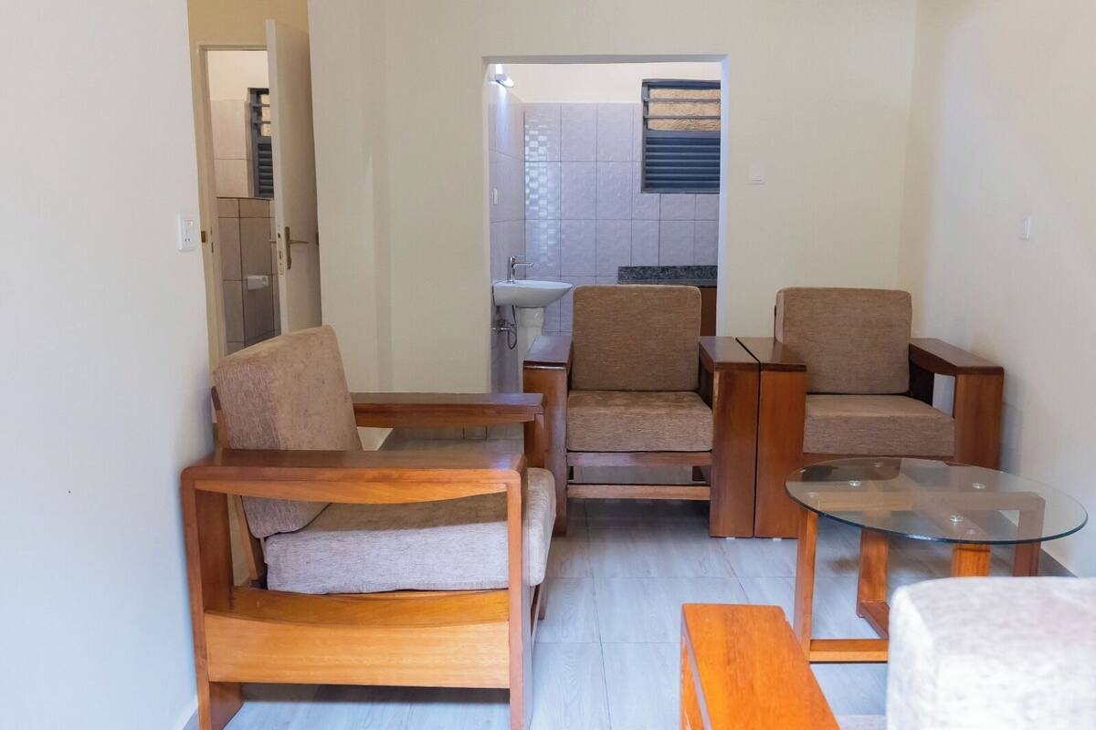 Ein modernes Wohnzimmer mit Holzmöbeln, darunter ein Sofa, Sessel und ein Glastisch.