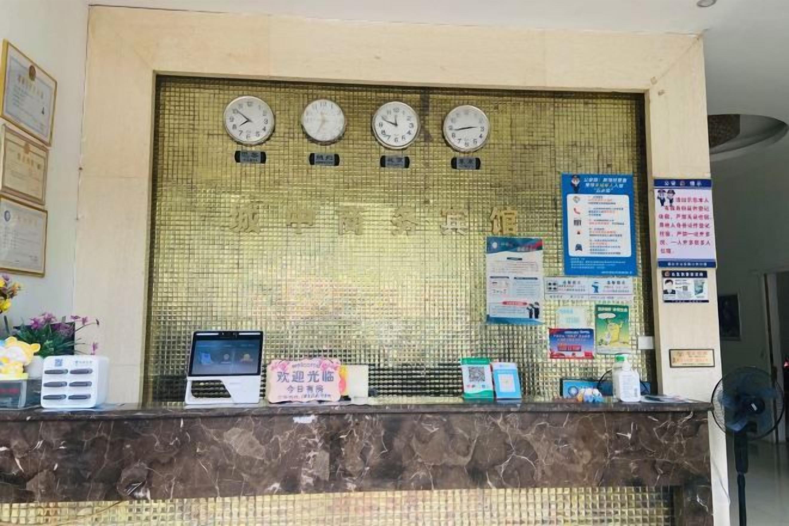 A reception desk with clocks, informational posters, and a laptop.