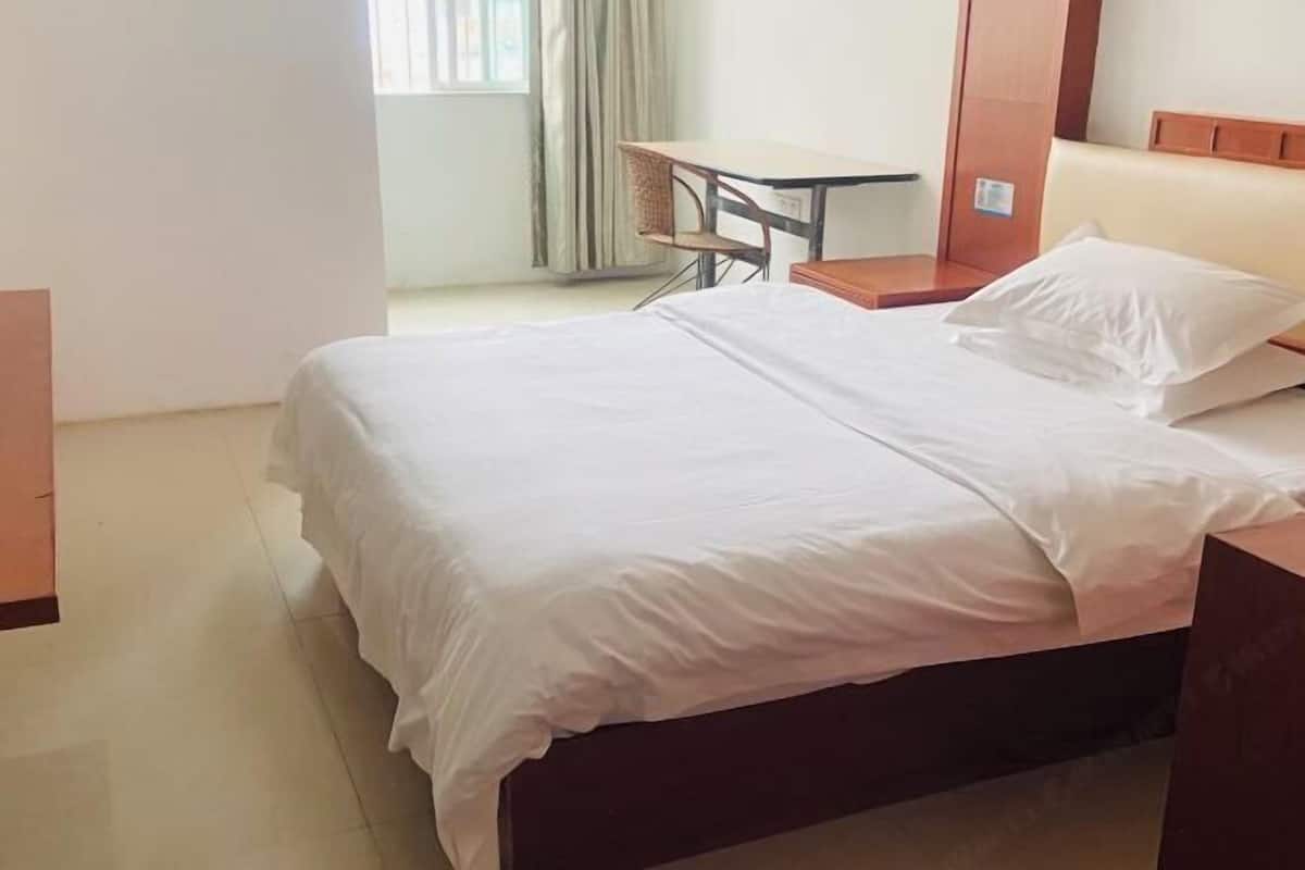 A hotel room with a bed, a small table, and a chair.