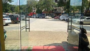 A parking lot with cars, a red mat, and a glass door entrance.