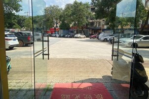 Un estacionamiento con coches, un tapete rojo y una entrada con puerta de cristal.