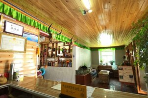 Un área de recepción con techo de madera, un mostrador de recepción y una cortina verde.