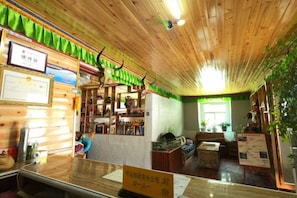 A reception area with a wooden ceiling, a reception desk, and a green curtain. - Daocheng Snowberg Inn (Daocheng County)