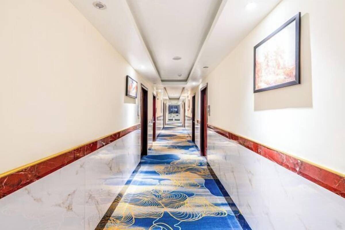 Ein Hotel-Flur mit einem gemusterten Teppich, Marmorböden und gerahmten Kunstwerken an den Wänden.