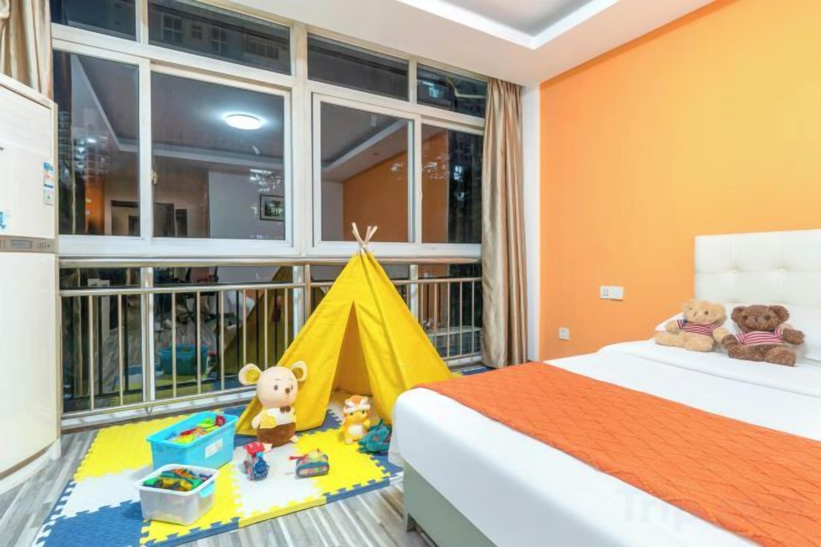 A room with a bed, a yellow tent, and two teddy bears on the bed.