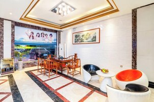 Un hall de hotel con mostrador de recepción, zona de estar y un ventanal grande.