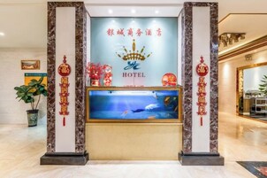 Una recepción de hotel con un acuario grande, elementos decorativos y un letrero con caracteres chinos.