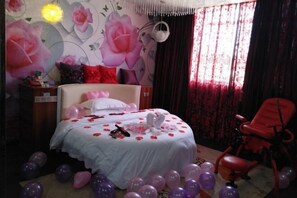 A bedroom with a bed, a red chair, and balloons. - Lingshan Yincheng Business Hotel (Lingshan)