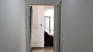 A narrow hallway with wooden flooring and a rug, leading to a room with a brown sofa and a window. - New Panoramic Villino in Porto Palo di Menfi Blue Flag ideal for families  (Menfi)