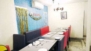 A restaurant with booths and tables set for dining, a birthday banner on the wall, and an air conditioning unit above the seating area. - Hotel Kawa (Jaipur)