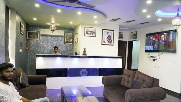 A reception area with a reception desk, two sofas, a coffee table, and a TV on the wall. - Hotel Kawa (Jaipur)