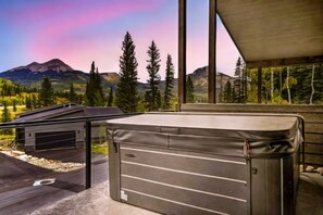 A modern cabin with a large window overlooking a mountainous landscape.
