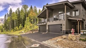 Et moderne hus med to etager, en garage, en balkon og en indkørsel med udsigt til et bjerg.