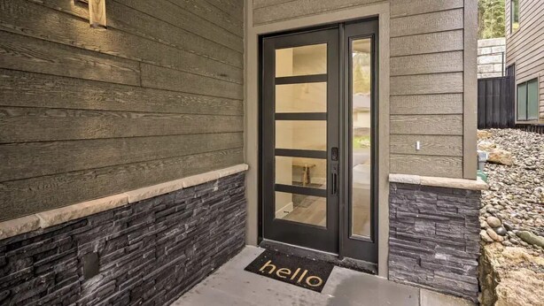 A modern exterior with a stone accent wall, a black door with glass panels, and a 'hello' mat at the entrance. - Mtn Views • Hot Tub • Trails Out Back • Sleeps 8 (Durango)