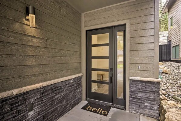 A modern exterior with a stone accent wall, a black door with glass panels, and a 'hello' mat at the entrance. - Mtn Views • Hot Tub • Trails Out Back • Sleeps 8 (Durango)