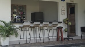A bar area with stools, a television, and a sign that says 'This is my happy place.' - Green D'mel Bali (Nusa Dua)