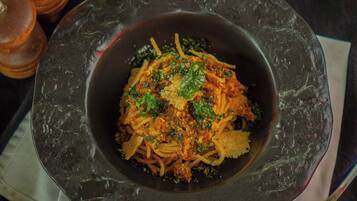 A bowl of pasta with a dark, textured bowl on a table.