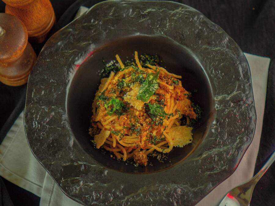 A bowl of pasta with a dark, textured bowl on a table.