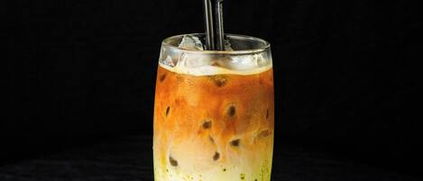 A glass of iced tea with a straw and a metal stirrer.