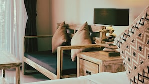 A cozy room with a wooden bed, a bedside table with a lamp, and a window with curtains. - Green D'mel Bali (Nusa Dua)