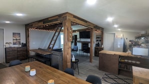 Una cocina acogedora con zona de comedor de madera, un banco empotrado y una escalera que lleva a un altillo.
