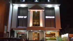A two-story building with a central entrance flanked by columns, a large window above the door, and a sign above the entrance. - Heritage Inn (Mysore)