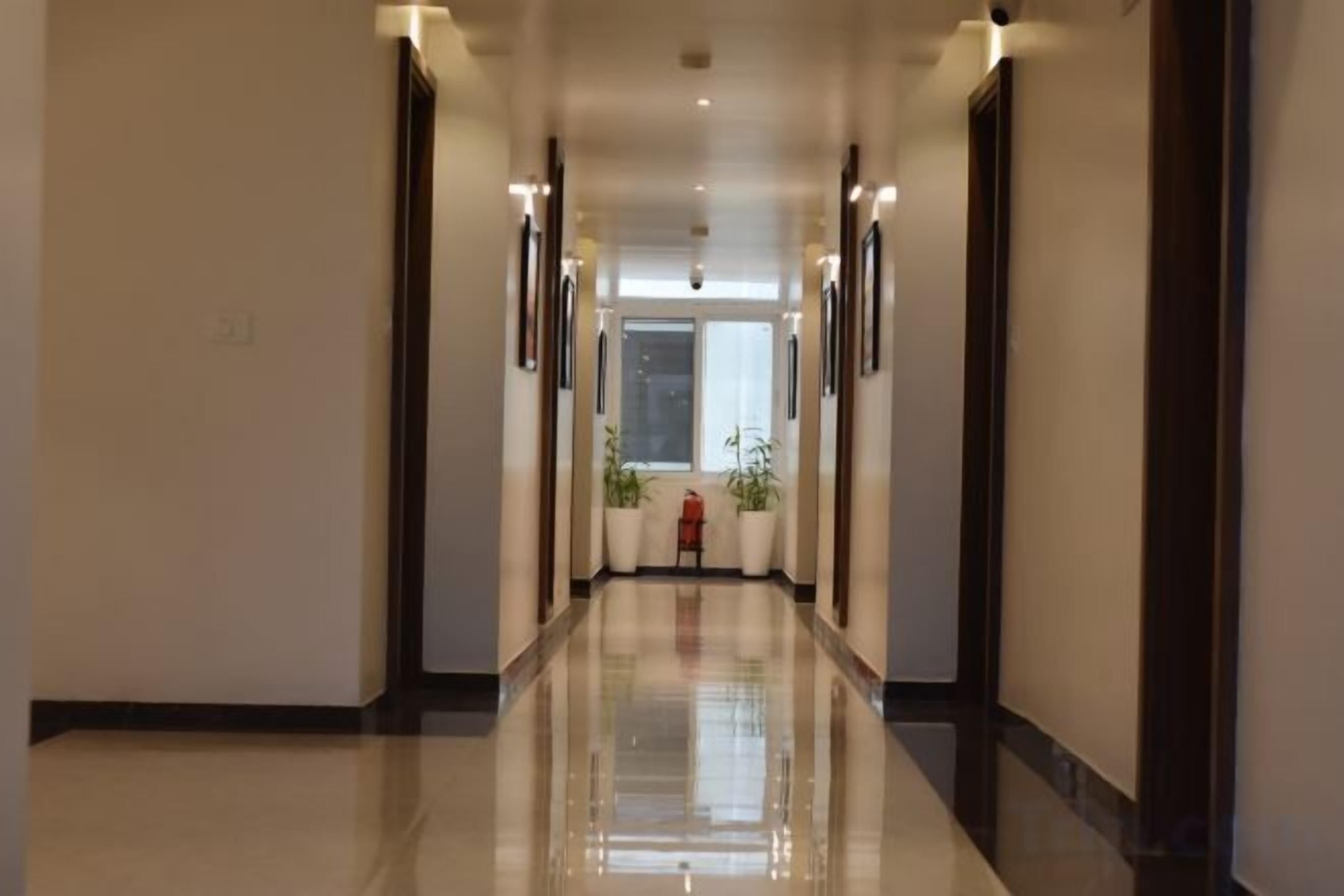 Un corridoio d'hotel con pavimento lucido, quadri alle pareti e una porta in fondo.