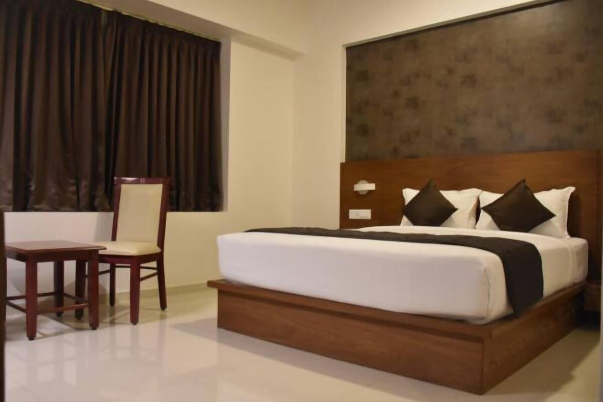 Une chambre d’hôtel avec un grand lit, une tête de lit en bois, un bureau et une chaise.
