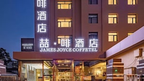 Un hotel con fachada moderna, señalización iluminada y una entrada visible con puertas de vidrio.