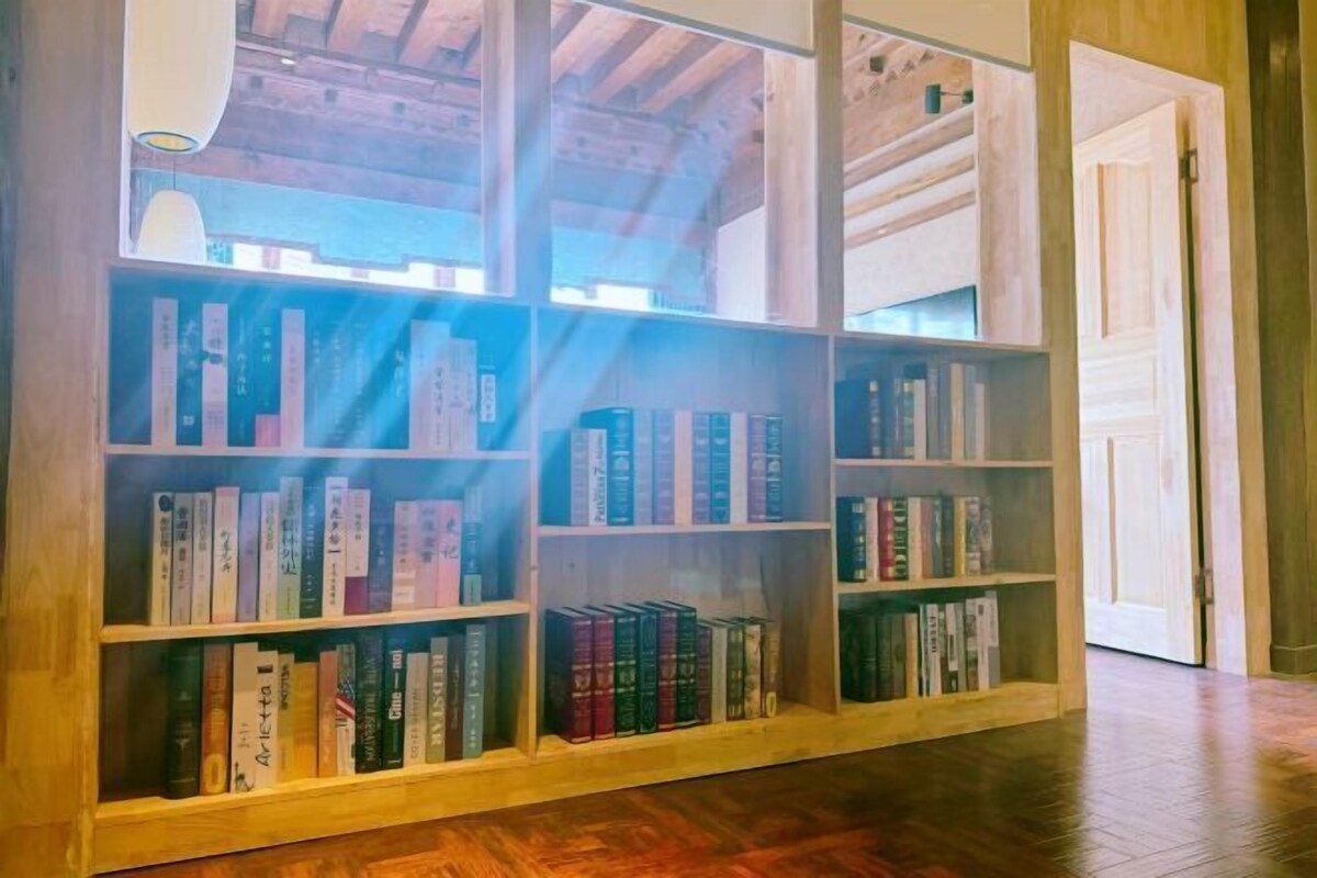 A wooden bookshelf with books, a wooden floor, and a door in the background.