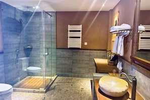 A bathroom with a glass-enclosed shower, a wooden vanity, and a large stone sink. - Shangri-La Fanyue Mountain Resort (Shangri-La)
