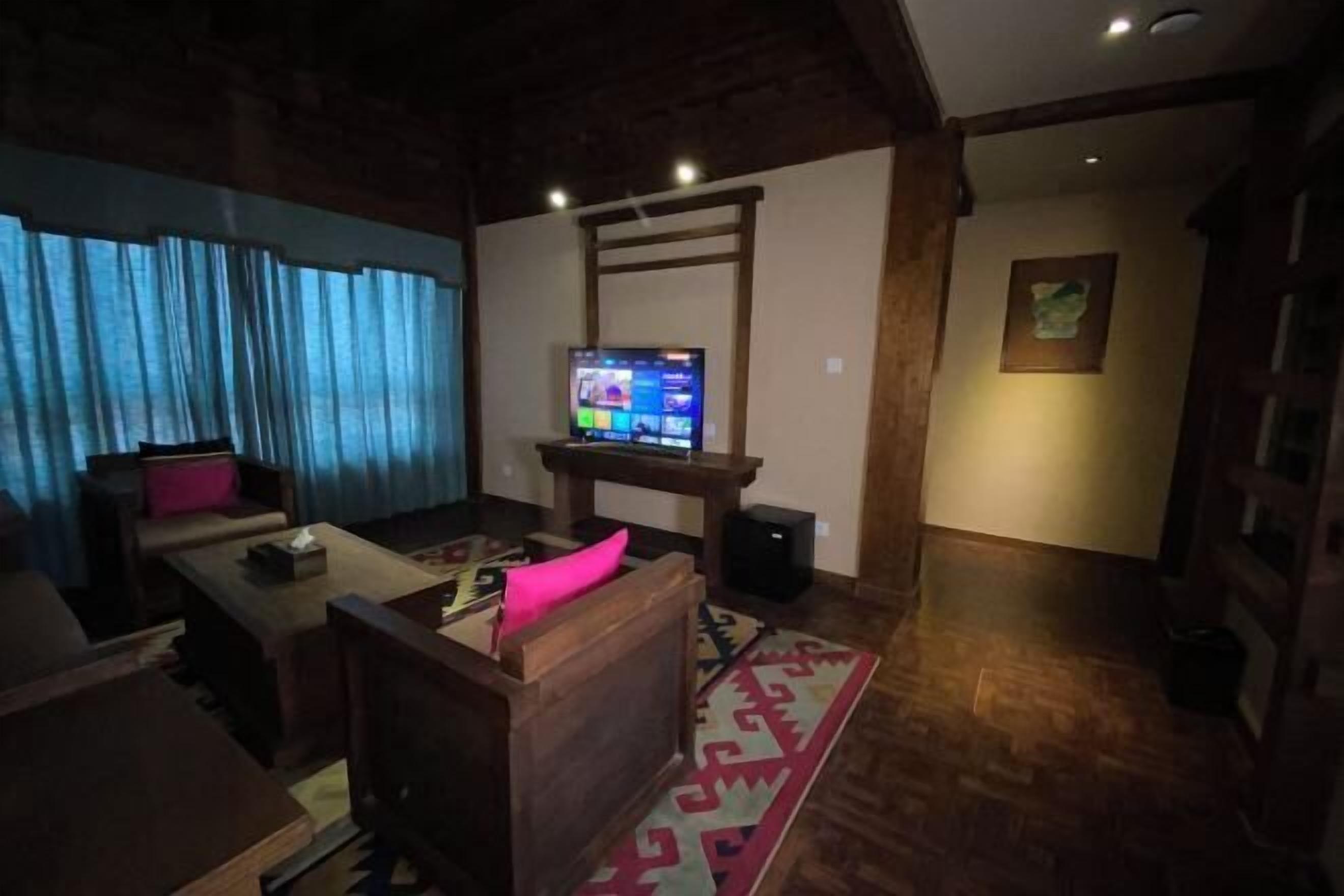 Ein Wohnzimmer mit Fernseher, Holzmöbeln und einem gemusterten Teppich.